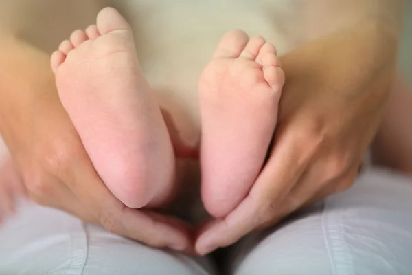 Mãos adultas segurando os pés do bebê, close-up — Fotografia de Stock