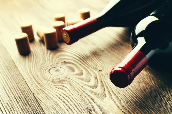 Szklana butelka wina z korkami na drewnianym tle stołu — Zdjęcie stockowe