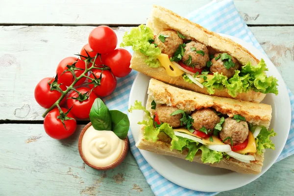 Homemade Spicy Meatball Sub Sandwich on plate, on wooden table background