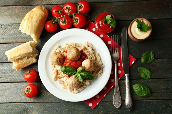 Pasta con polpette su piatto, su fondo tavola in legno — Foto Stock