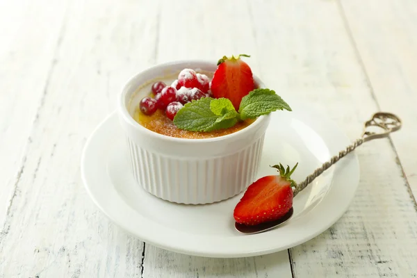 Postre de crema brulee con fresas frescas y hojas de menta, sobre fondo de madera de color —  Fotos de Stock