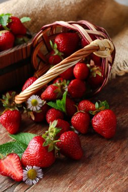 ahşap arka plan üzerinde hasır sepet içinde kırmızı olgun çilek