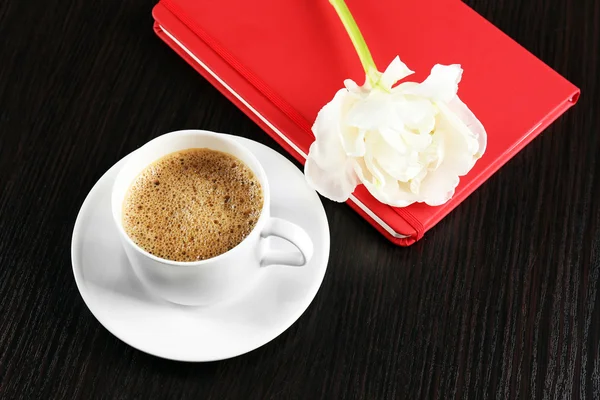 Filiżanka kawy z notebooka i świeżych kwiatów na drewnianym stole tło — Zdjęcie stockowe