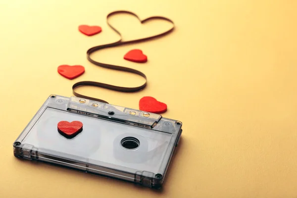 Audiocassetta con nastro magnetico a forma di cuore su sfondo giallo — Foto Stock