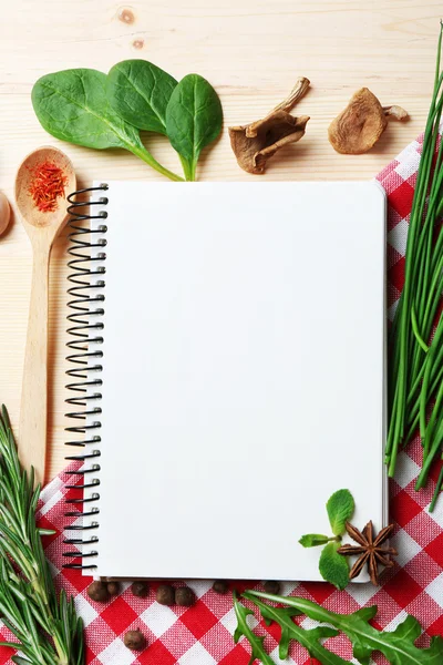 Livro de receitas aberto com ervas frescas e especiarias em fundo de madeira — Fotografia de Stock