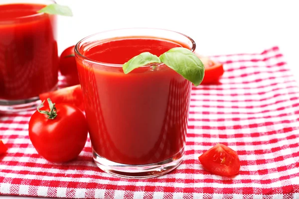 Glasses of fresh tomato juice on checkered napkin, closeup — Stok fotoğraf