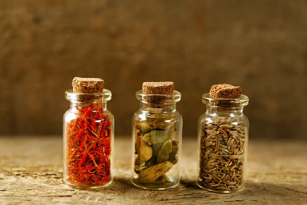 Assortiment van specerijen in glazen flessen op houten achtergrond — Stockfoto