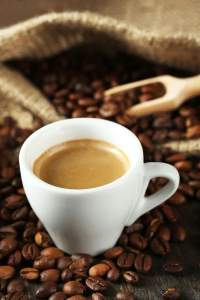 Tasse Kaffee mit Bohnen auf dem Tisch aus nächster Nähe — Stockfoto