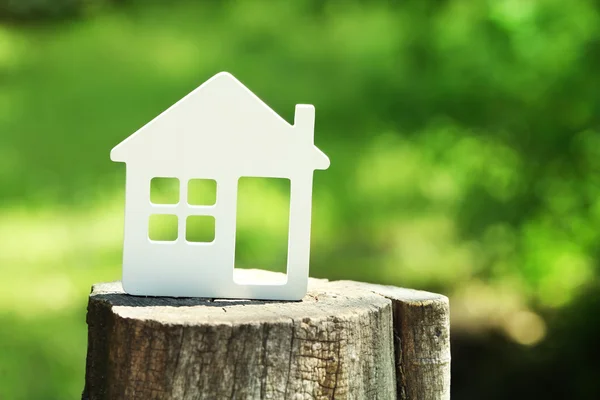 Modelo pequeno de casa no toco no fundo borrado verde — Fotografia de Stock