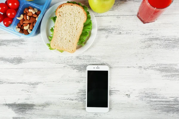 Food and mobile phone on wooden background — Stock Photo, Image