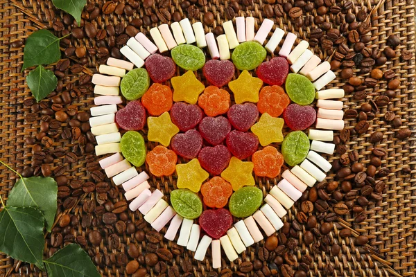 Gummy candies and marshmallow arranged in heart shape on table close up — Stock Photo, Image