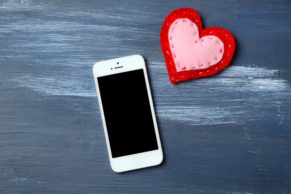 White smart phone with heart on wooden desk. — ストック写真
