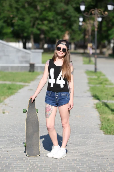 Schöne tätowierte Mädchen mit Skateboard, im Freien — Stockfoto