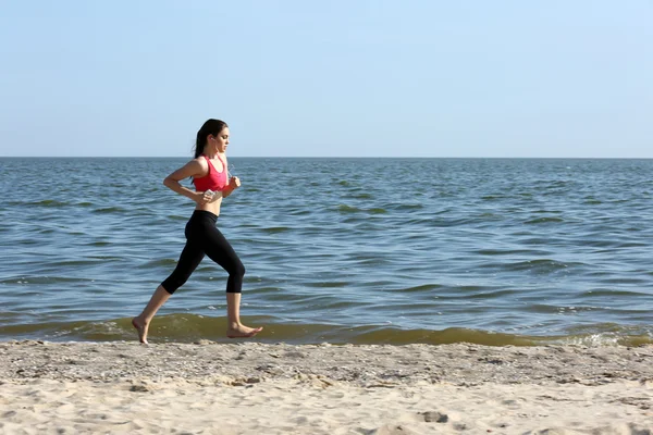 Jonge vrouw joggen op strand — Stockfoto