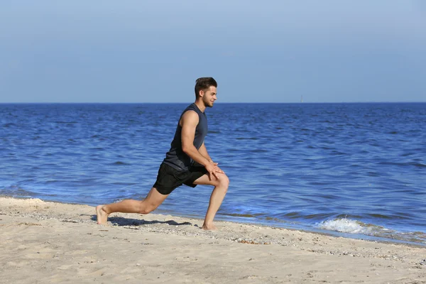 Ung man sportiga gör övning på stranden — Stockfoto