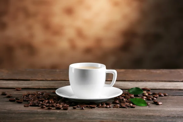 Cup of coffee and beans on blurred background — Stock Photo, Image