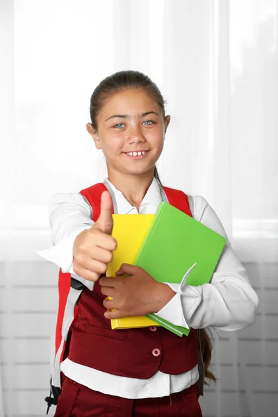 Mooi meisje in school uniform met rugzak en boeken — Stockfoto