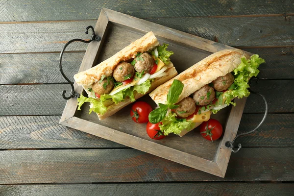Сэндвич с фрикадельками на подносе, на деревянном фоне — стоковое фото