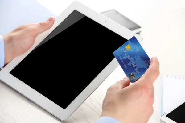 Man holding credit card and tablet on workplace background — Stock Photo, Image