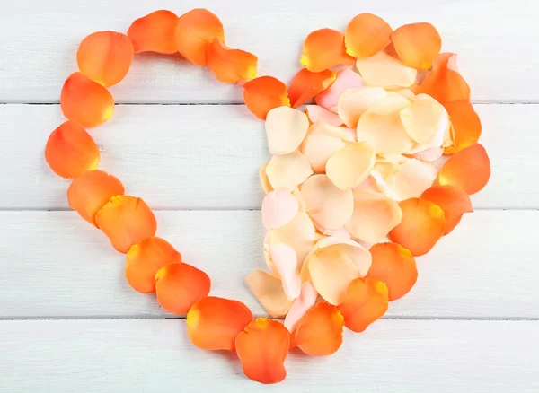 Hermoso corazón de pétalos de rosa sobre fondo de madera — Foto de Stock