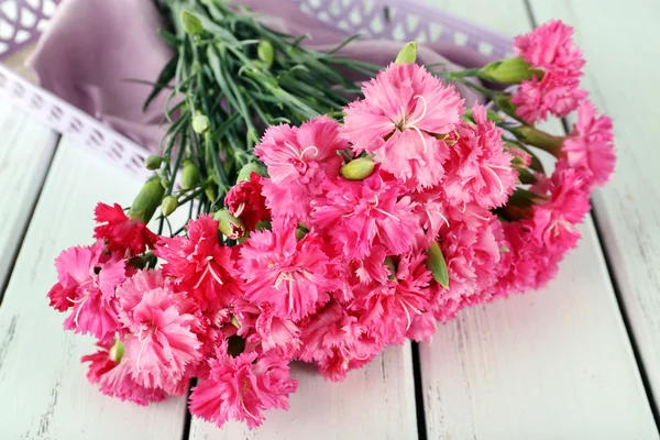 Belo buquê de cravo rosa na mesa de madeira de perto — Fotografia de Stock