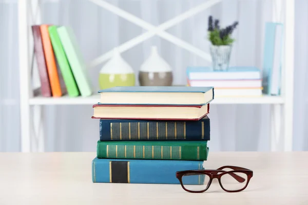 Stapel boeken met een bril op houten tafel op kamer — Stockfoto