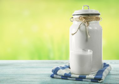 Retro can for milk and glass of milk on wooden table, on green background