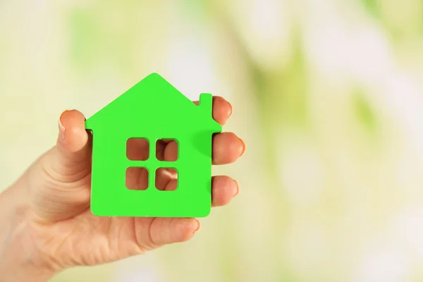 Female hand with model of house on blurred background — Stock Photo, Image