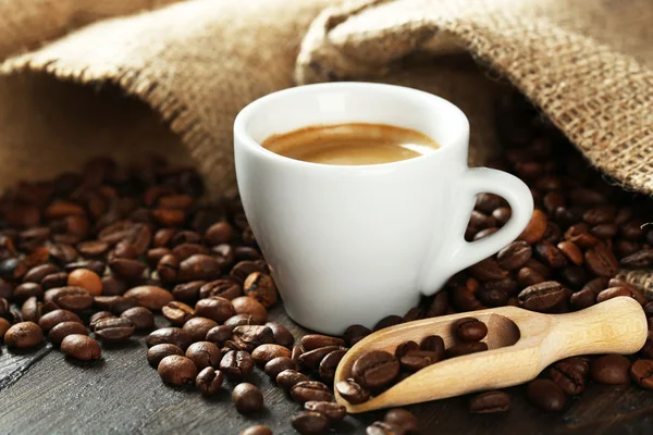 Xícara de café com grãos na mesa de perto — Fotografia de Stock