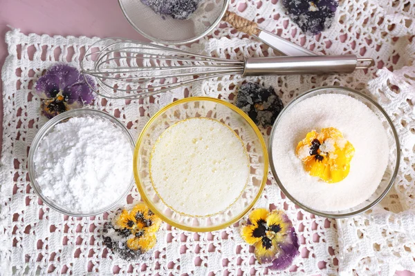 Fazendo flores violetas cristalizadas com claras de ovo e açúcar, na cor de fundo de madeira — Fotografia de Stock