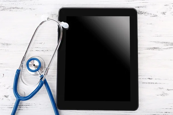 Tablet y estetoscopio azul sobre fondo de madera —  Fotos de Stock