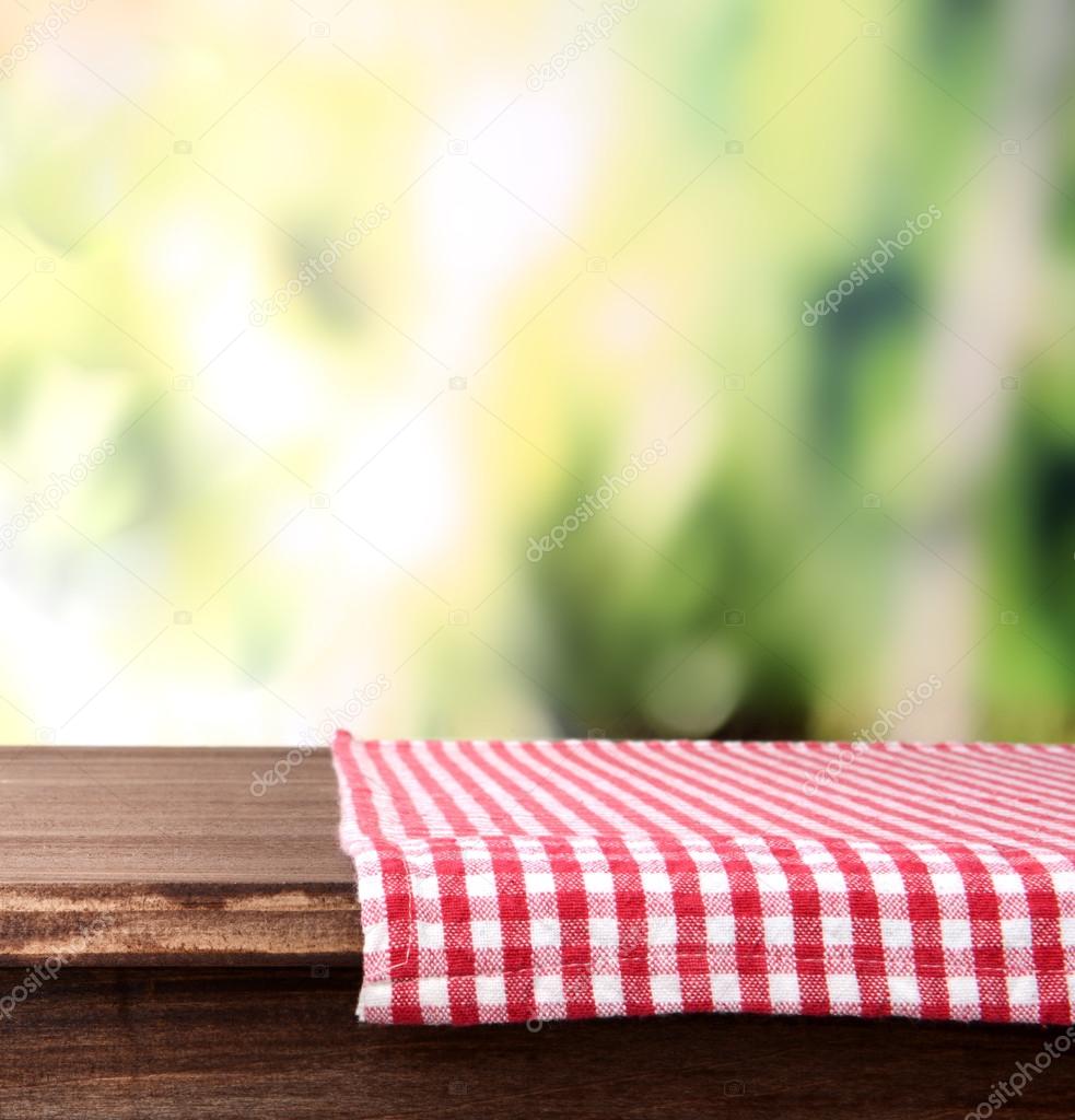 Empty wooden table with napkin on bright background