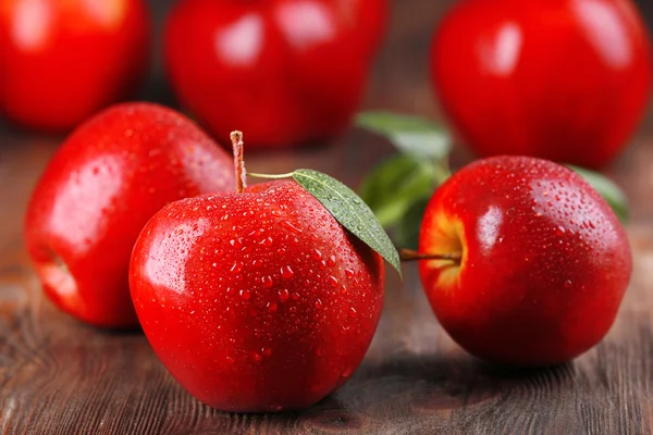 Red apples with droplets on wooden table, closeup — Stock Photo, Image