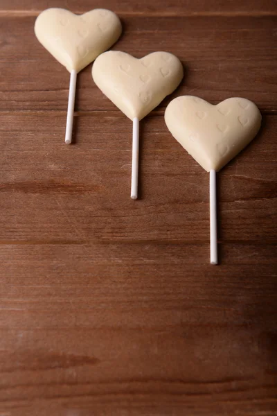 Chocolade snoepjes in de vorm van harten op houten achtergrond — Stockfoto