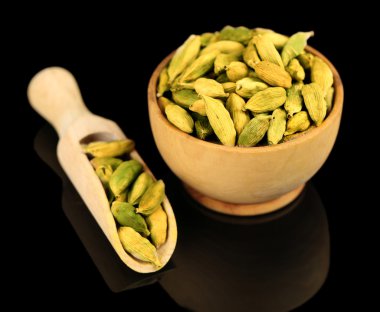 Cardamom in wooden bowl, on black background