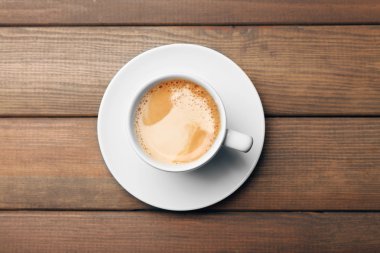 Bir fincan kahve, ahşap masa, üst manzara.