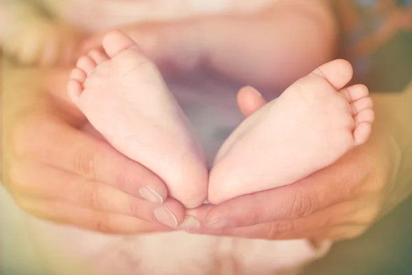 Adult hands holding baby feet, closeup — Stock Photo, Image