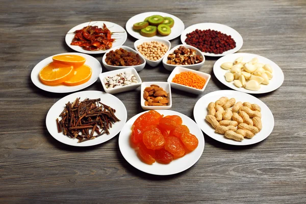 Different products on saucers on wooden table, closeup — Stock Photo, Image