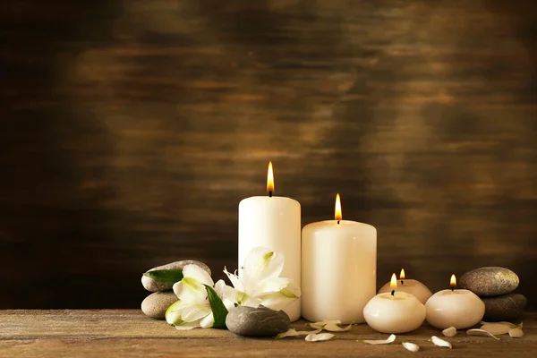 Bela composição com velas e pedras de spa em fundo de madeira — Fotografia de Stock