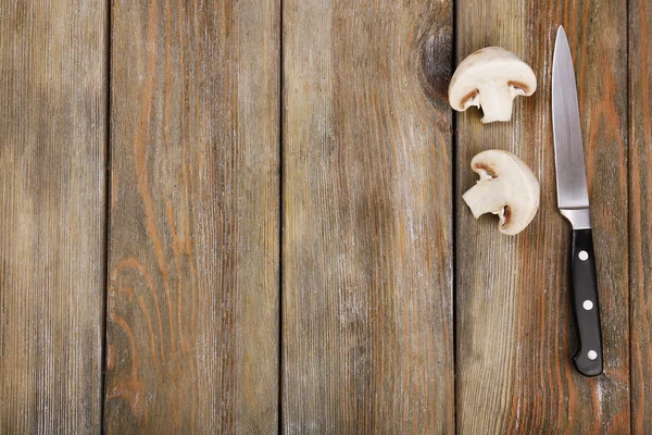 Helften van paddenstoel met mes op houten achtergrond — Stockfoto