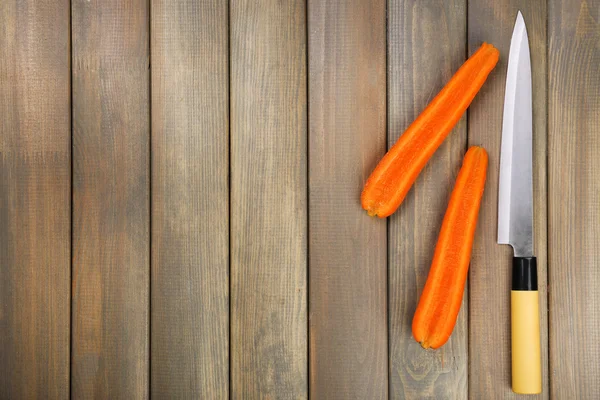 Halves of carrot with knife on wooden background — Stock Photo, Image