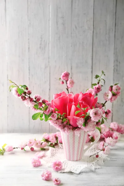 Bouquet de printemps en tasse colorée sur fond en bois de couleur — Photo