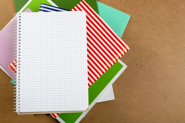 Notebook on top of pile of books and magazines on wooden background — Stock Photo, Image