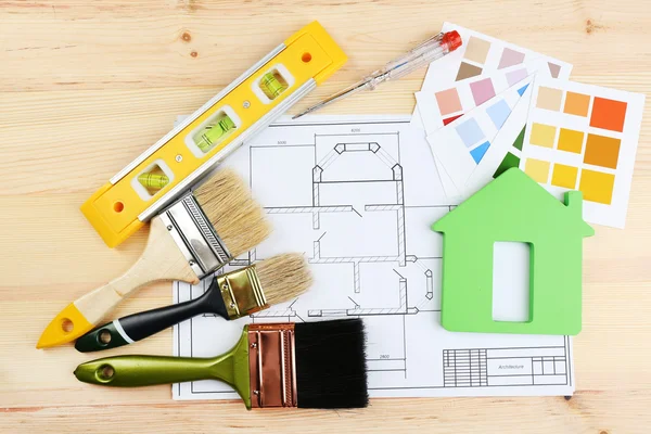 Instrumentos de construcción, plano, muestras de color y cepillos sobre fondo de mesa de madera — Foto de Stock