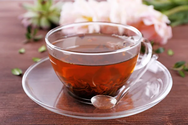 Чашка травяного чая с тюльпанами на деревянном столе, крупным планом — стоковое фото