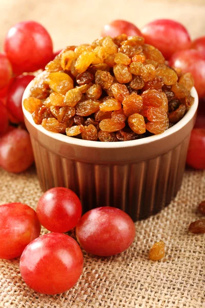 Raisins in bowl with grapes on table close up — Stock Photo, Image