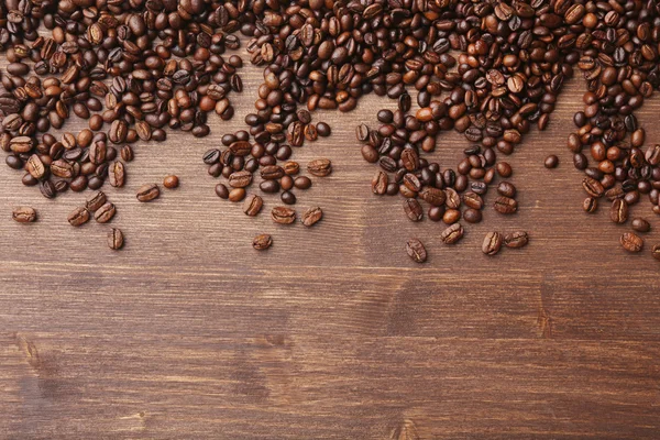 Grãos de café em fundo de madeira — Fotografia de Stock