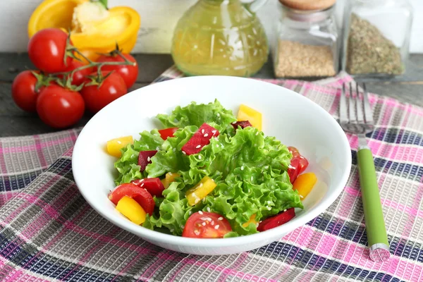 Bowl of fresh green salad on table with napkin, closeup — Stock Photo, Image