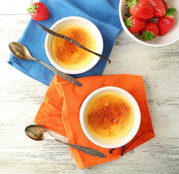 Creme Brulee Dessert mit frischen Erdbeeren auf Serviette, auf farbigem Holzhintergrund — Stockfoto