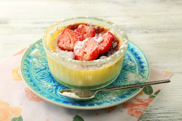 Crema brulee dessert con fragole fresche su tovagliolo, su sfondo di legno a colori — Foto Stock